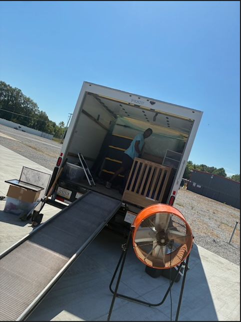 Two men and a child unpacking boxes in a bright living room.