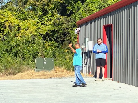 Man standing beneath a tree on a mountain, overlooking a foggy valley at sunrise.