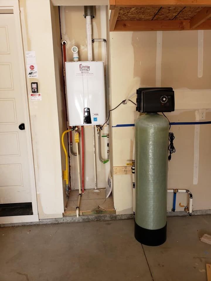 A water filter is sitting next to a water heater in a garage.