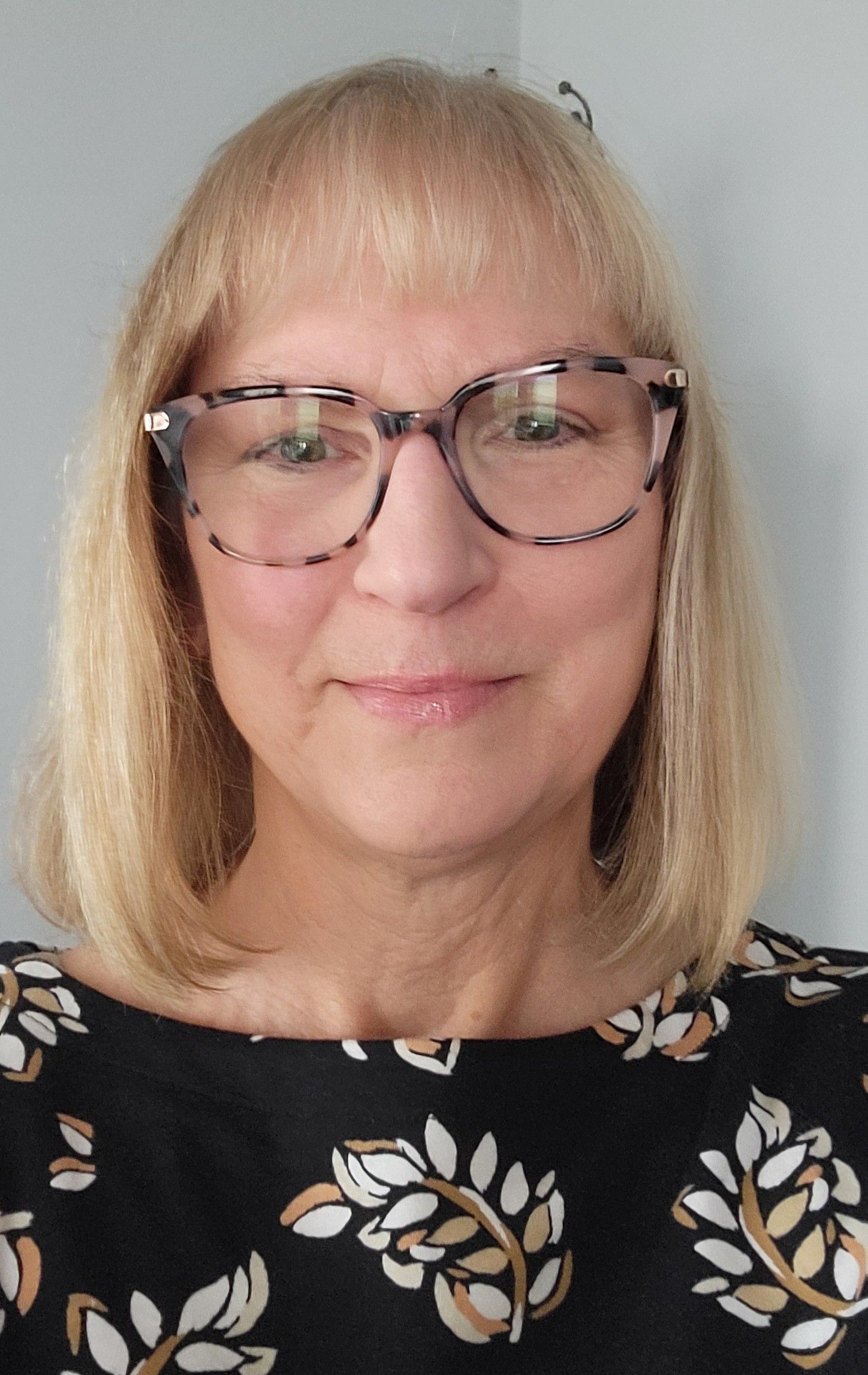 A woman wearing glasses and a black shirt with leaves on it.