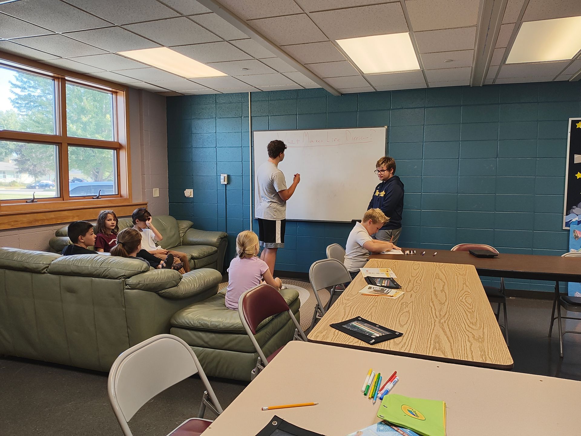 A group of children are sitting around a table in a room.