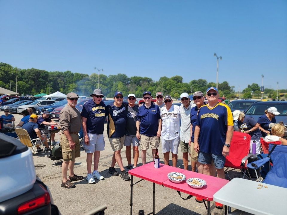 A group of men are posing for a picture in a parking lot.