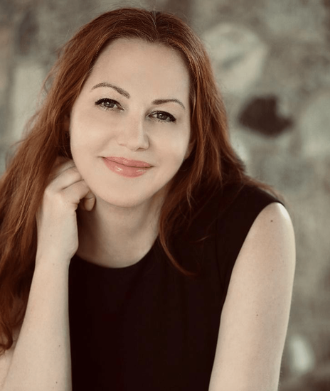 A woman with long red hair is wearing a black tank top