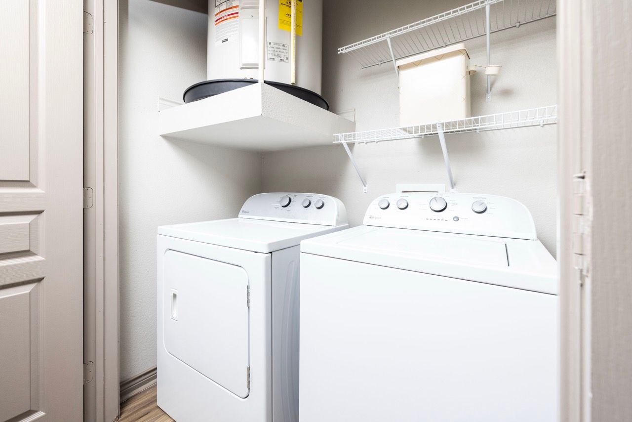 Laundry closet with front-loading dryer and top-loading washer, white appliances, shelving above.