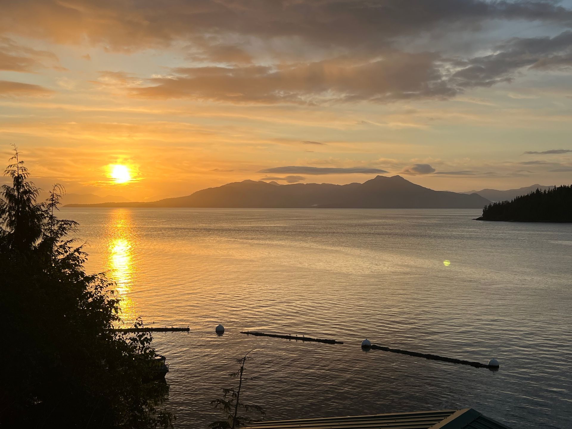 Sunset over calm water, with mountains on the horizon.