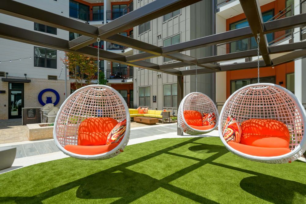 a group of hanging chairs sitting on top of a lush green lawn .