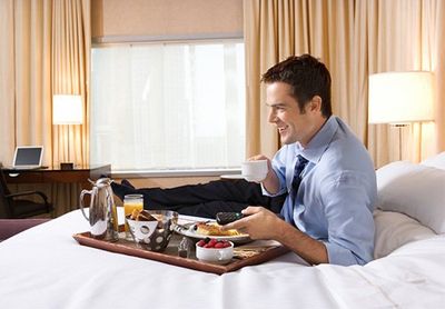 Man eating breakfast on bed in motel room — lodging services in Greenville, NC.