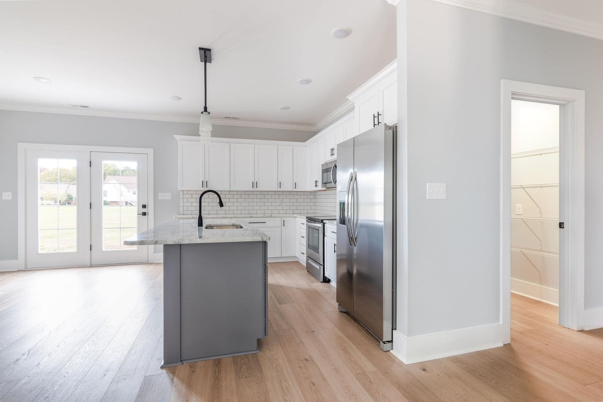 A kitchen with white cabinets , stainless steel appliances and a large island.