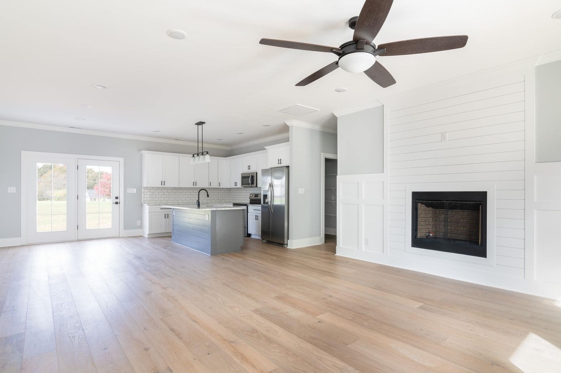 An empty living room with hardwood floors and a ceiling fan.