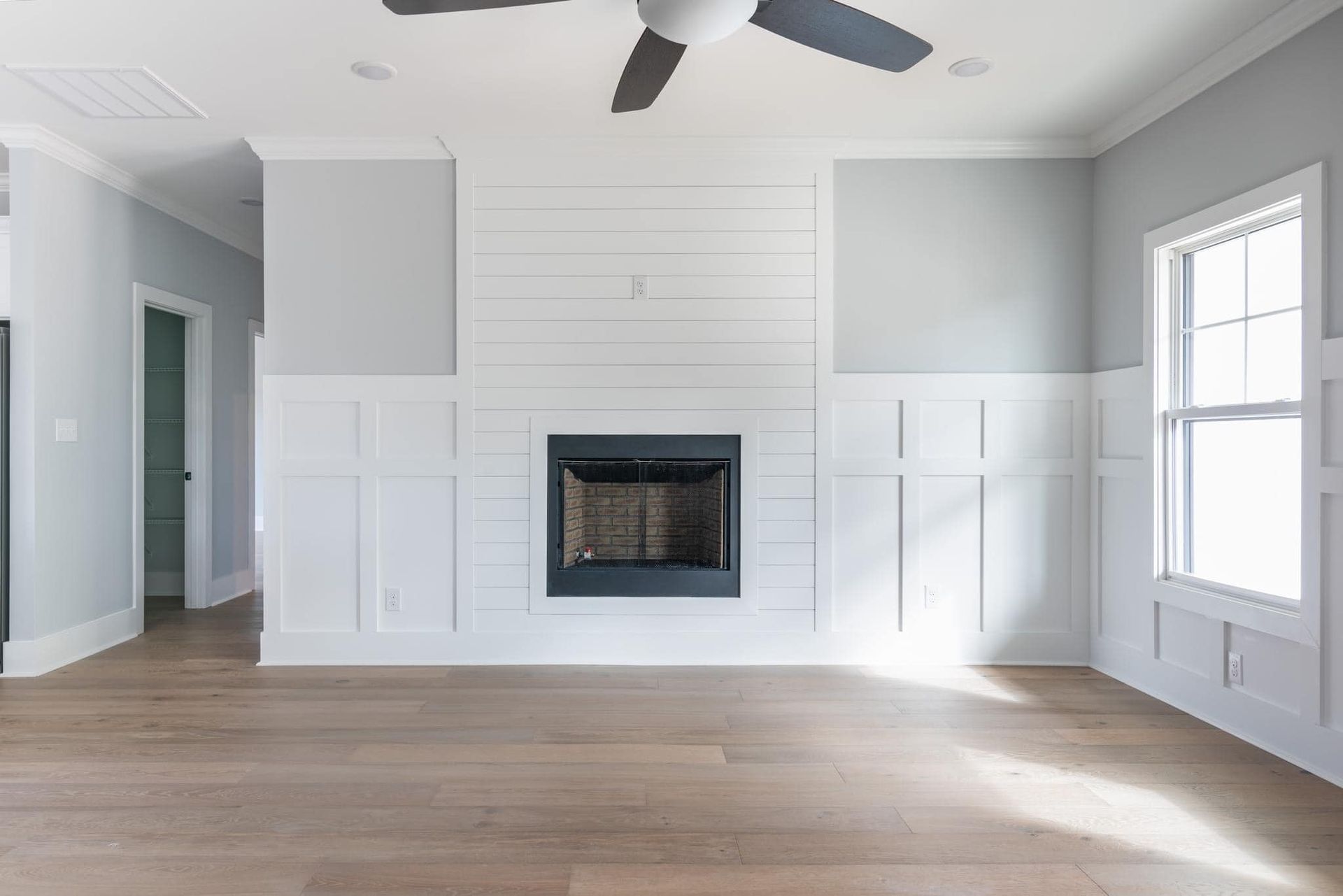 An empty living room with a fireplace and a ceiling fan.