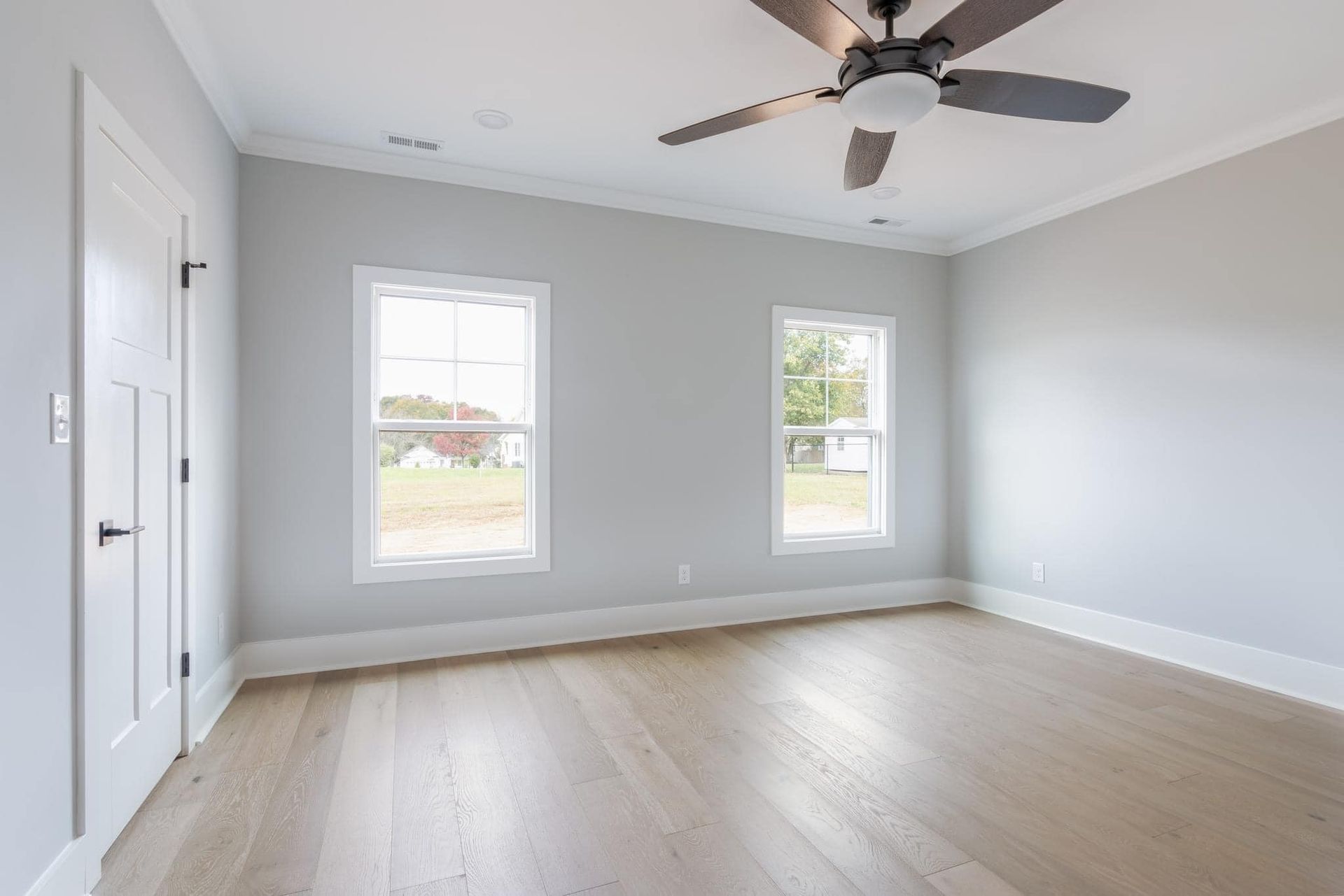 An empty bedroom with hardwood floors and a ceiling fan.