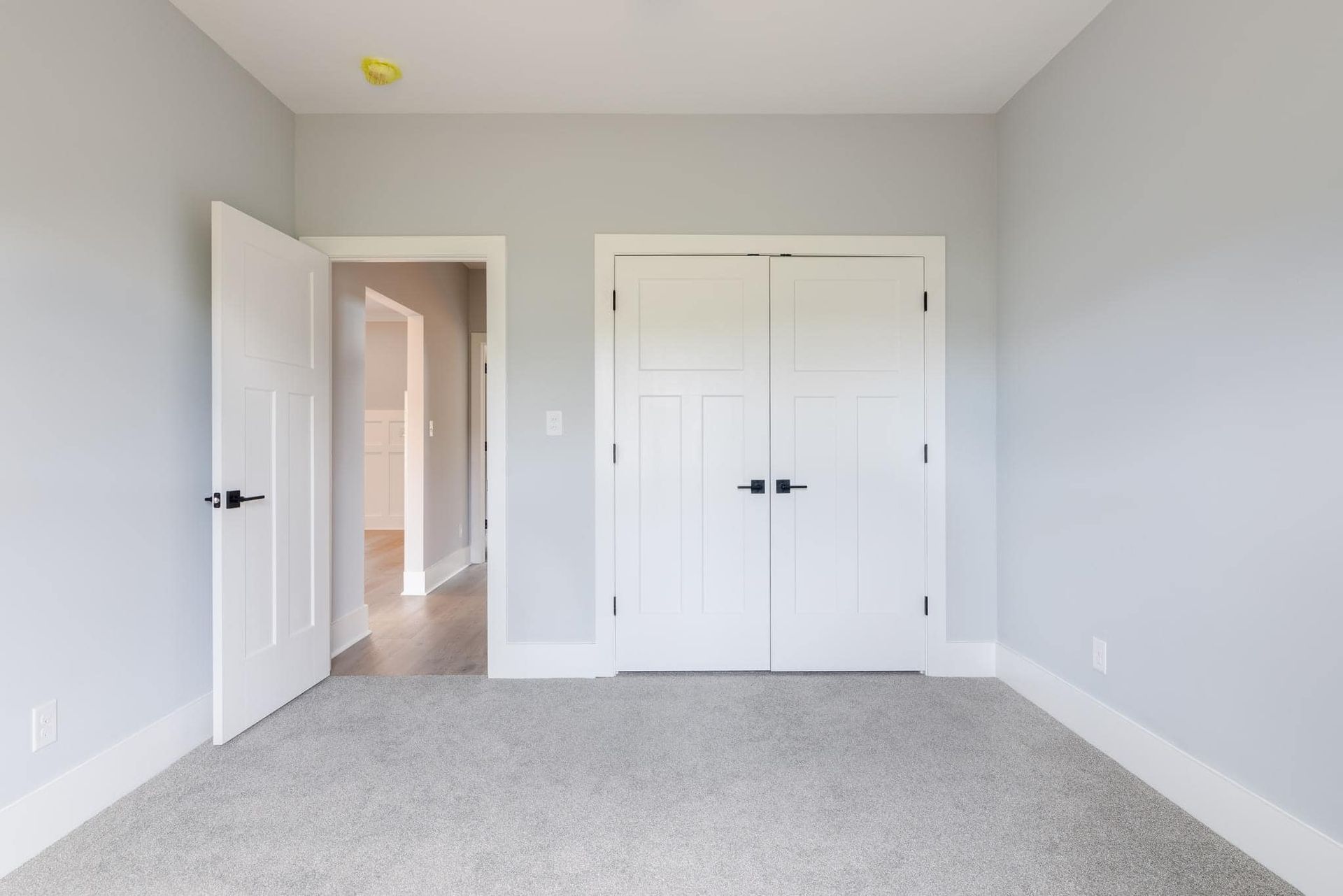 An empty bedroom with a carpeted floor and white walls.