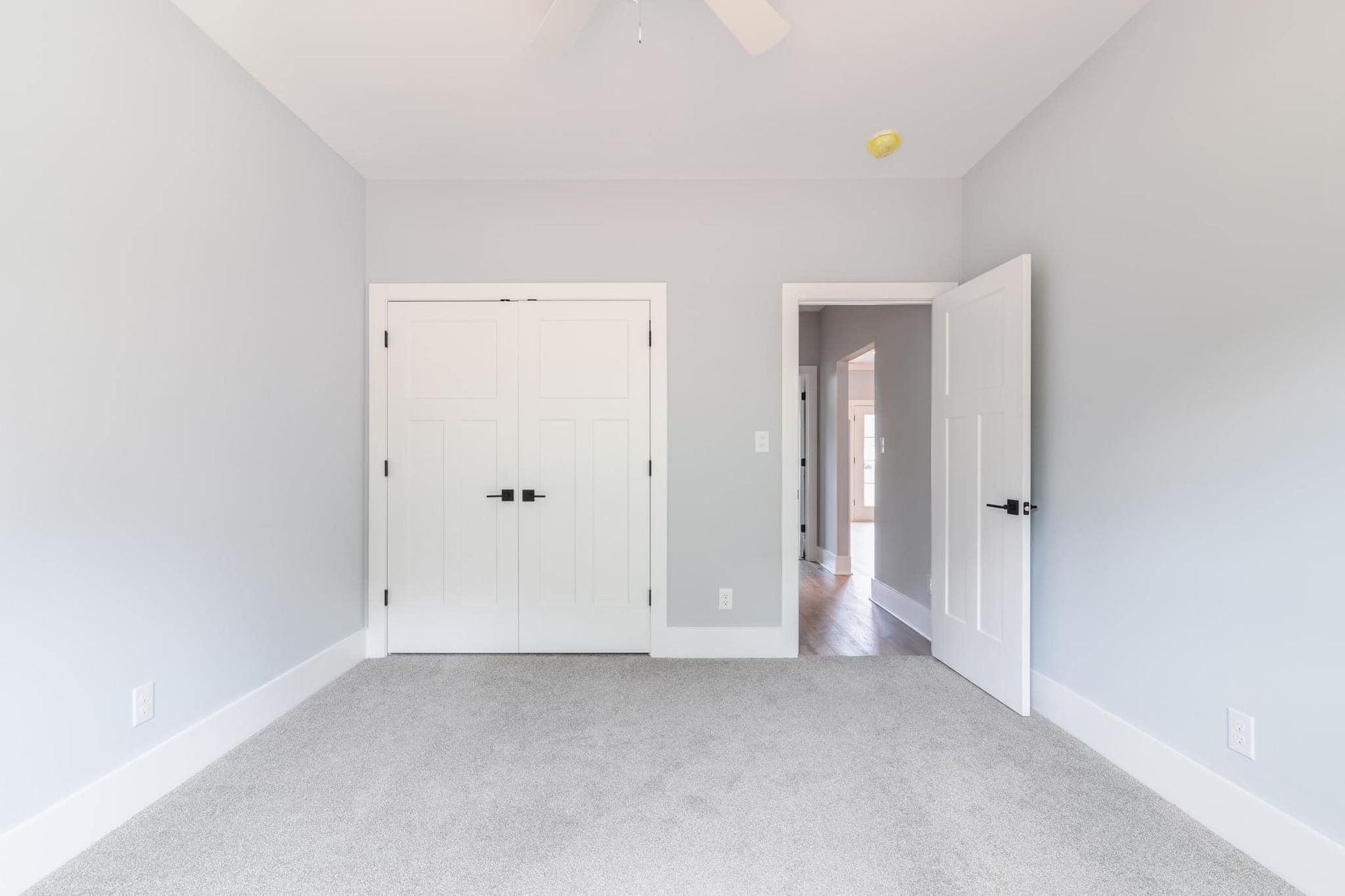 An empty bedroom with a carpeted floor and a ceiling fan.