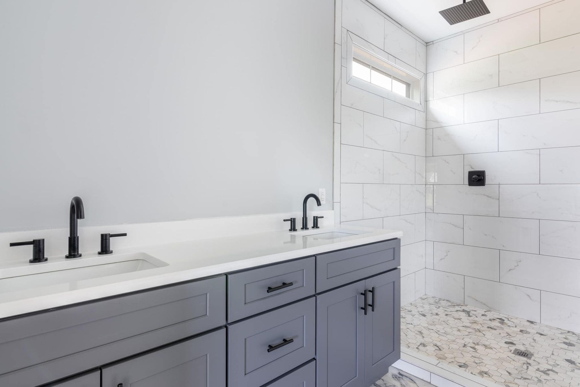 A bathroom with two sinks and a walk in shower.