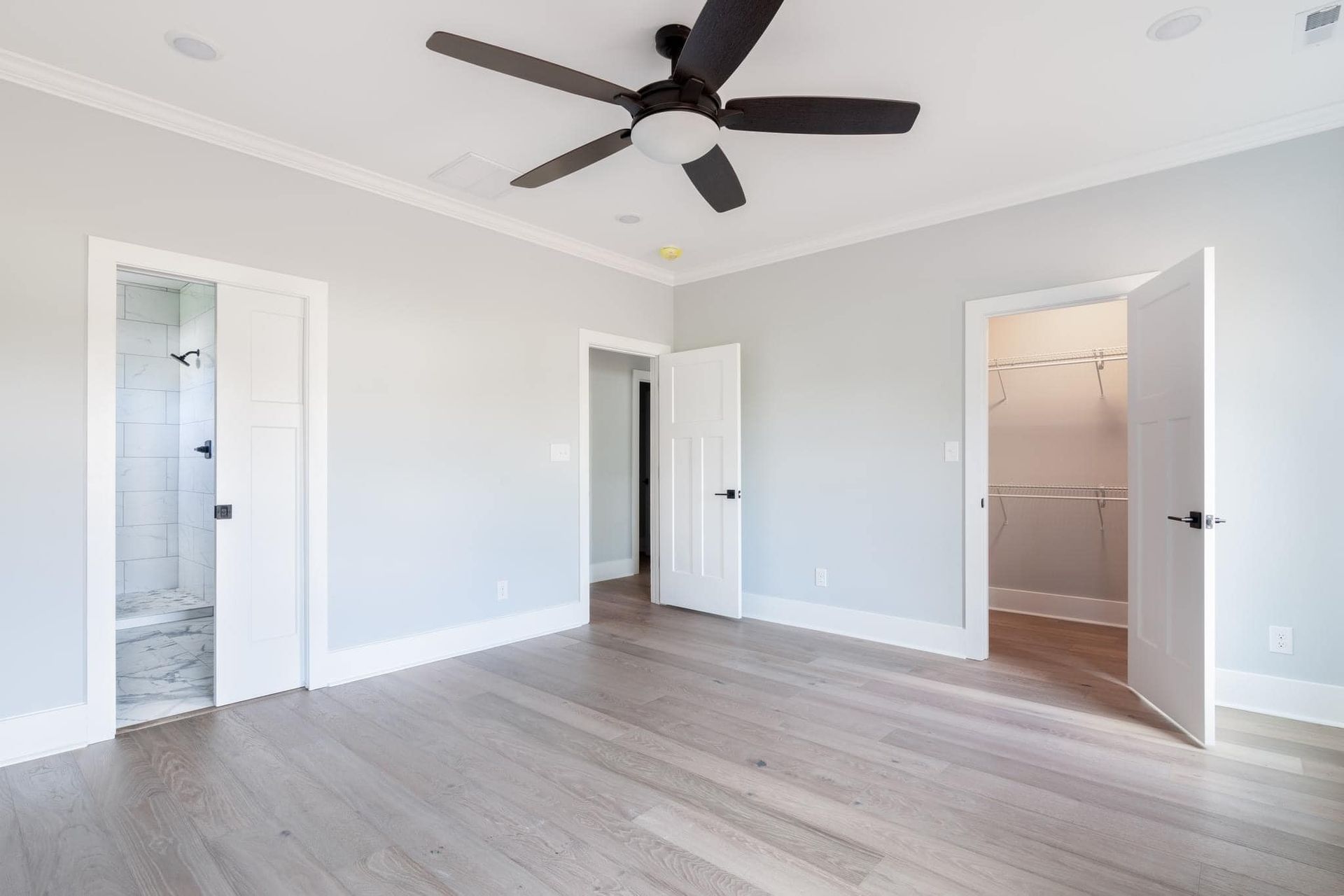 An empty bedroom with hardwood floors and a ceiling fan.