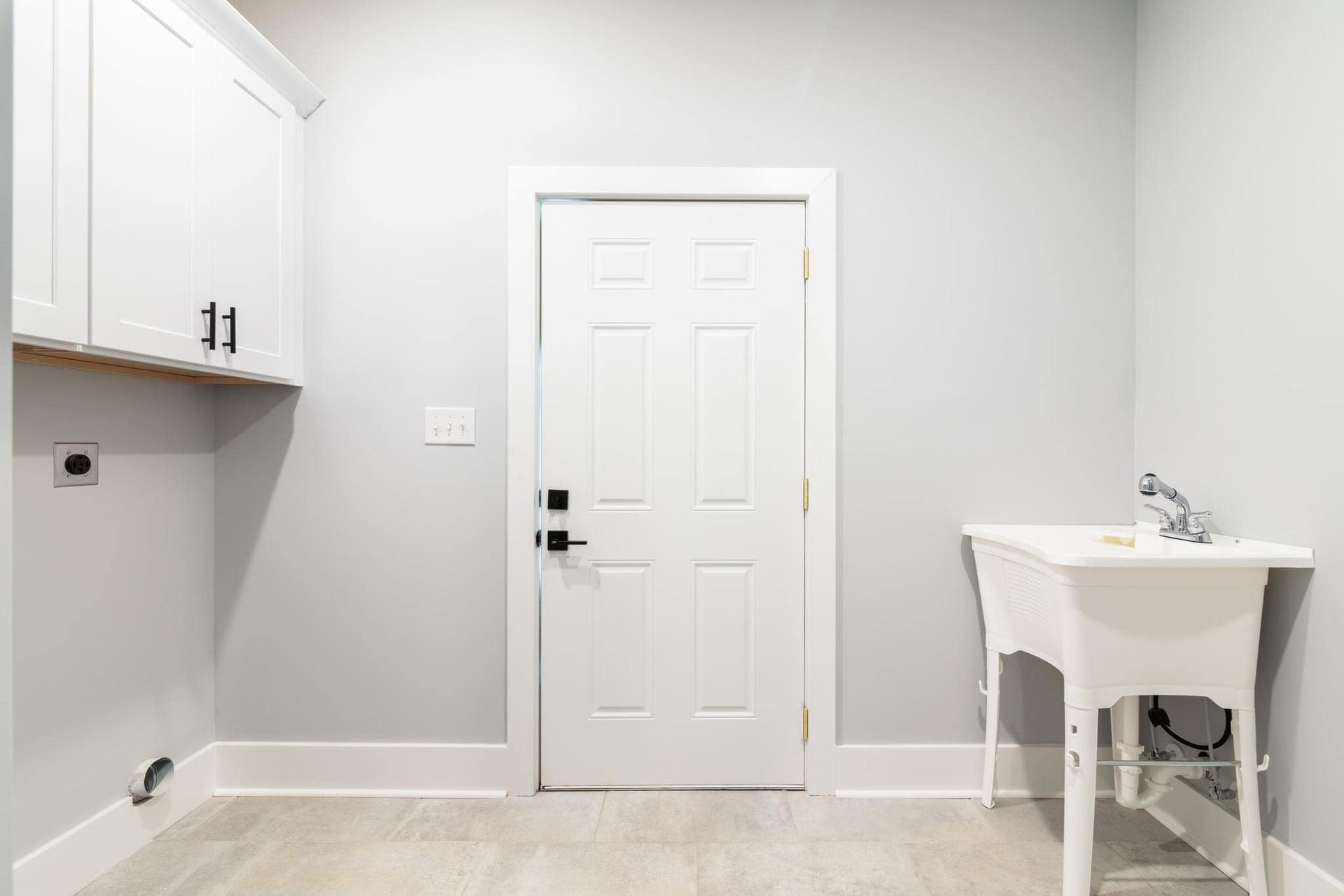 A laundry room with a sink and a door.