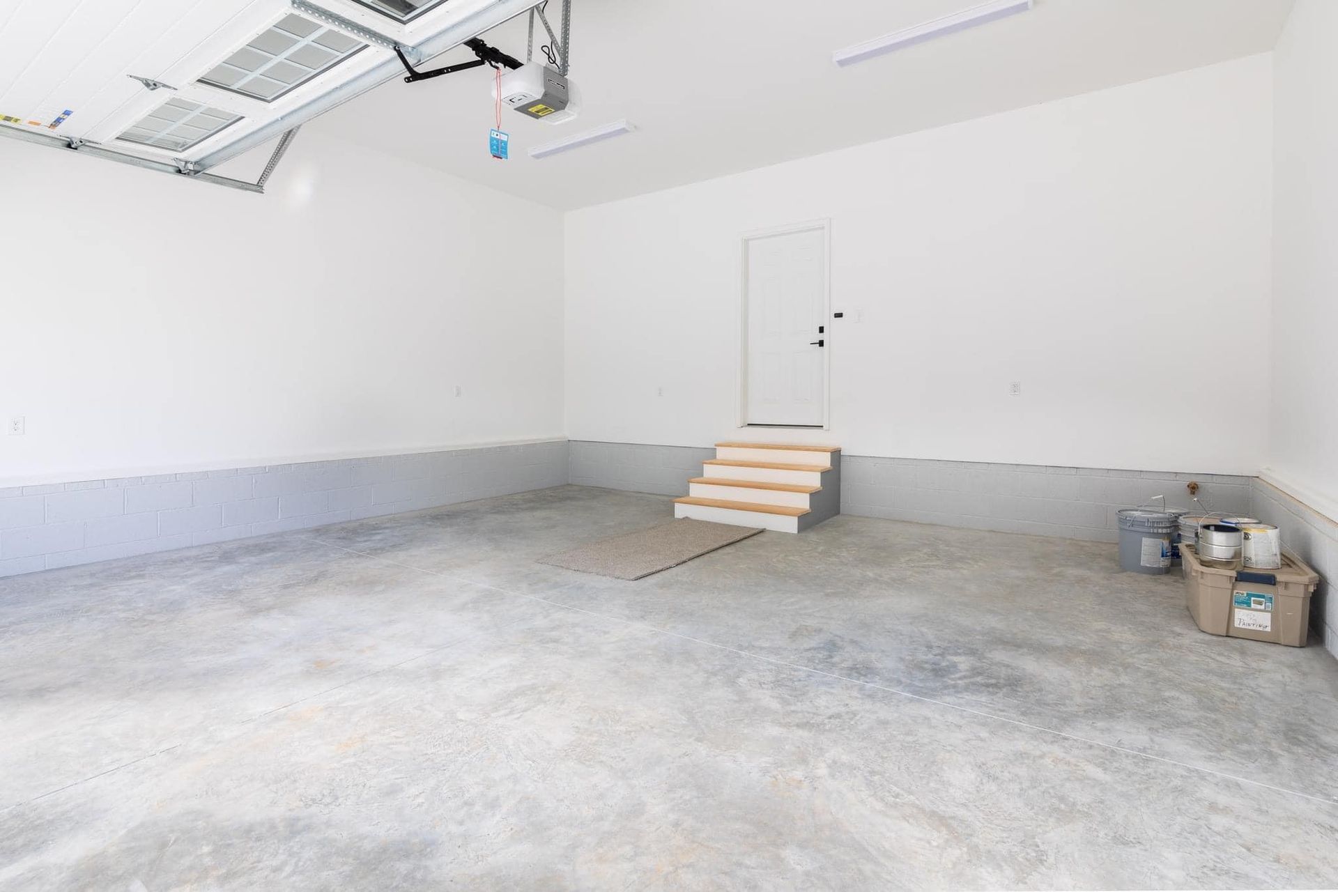 An empty garage with a door and stairs.