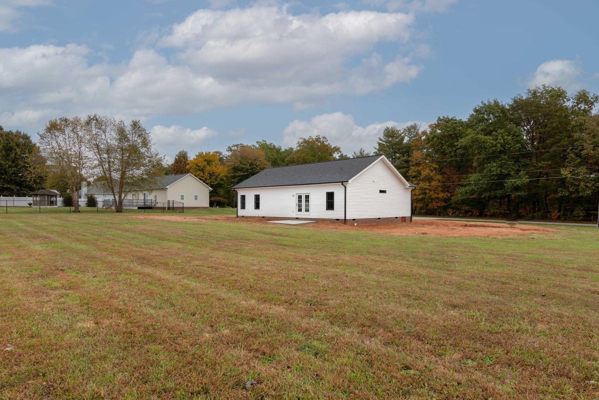 A white house is sitting in the middle of a grassy field.