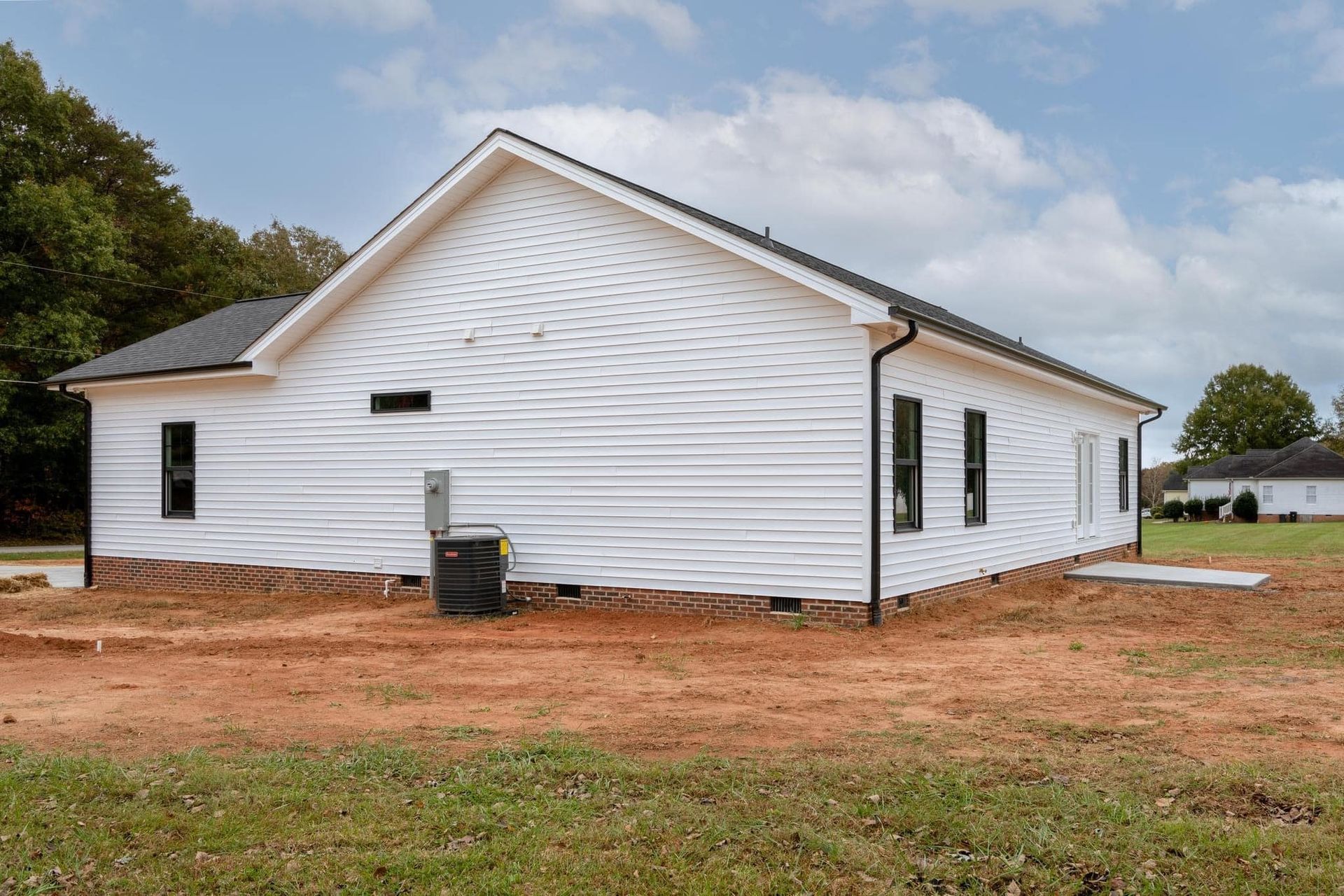 A white house is sitting in the middle of a dirt field.