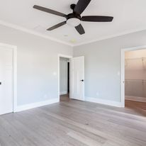 An empty bedroom with hardwood floors and a ceiling fan.