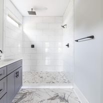 A bathroom with a walk in shower and a sink.