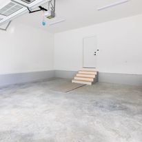 An empty garage with stairs leading up to the door.