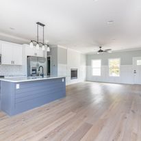 A kitchen with a large island in the middle of the room and hardwood floors.