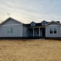 A large house is sitting on top of a dirt field.