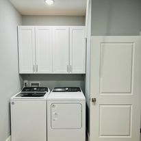 A laundry room with a washer and dryer and white cabinets.