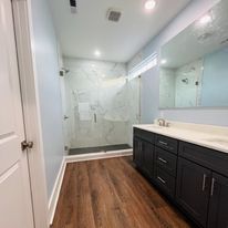 A bathroom with a walk in shower , sink , and mirror.