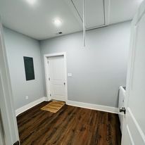 An empty room with hardwood floors and gray walls.