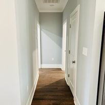 A long hallway with hardwood floors and white walls in a house.