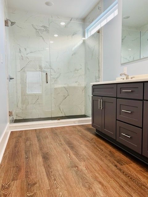 A bathroom with hardwood floors and a walk in shower.