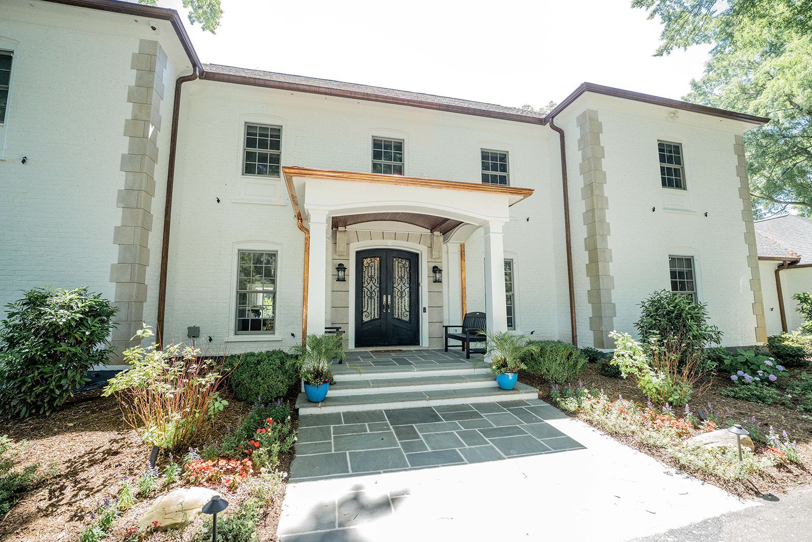A large white house with a black door and a pergola over the entrance.