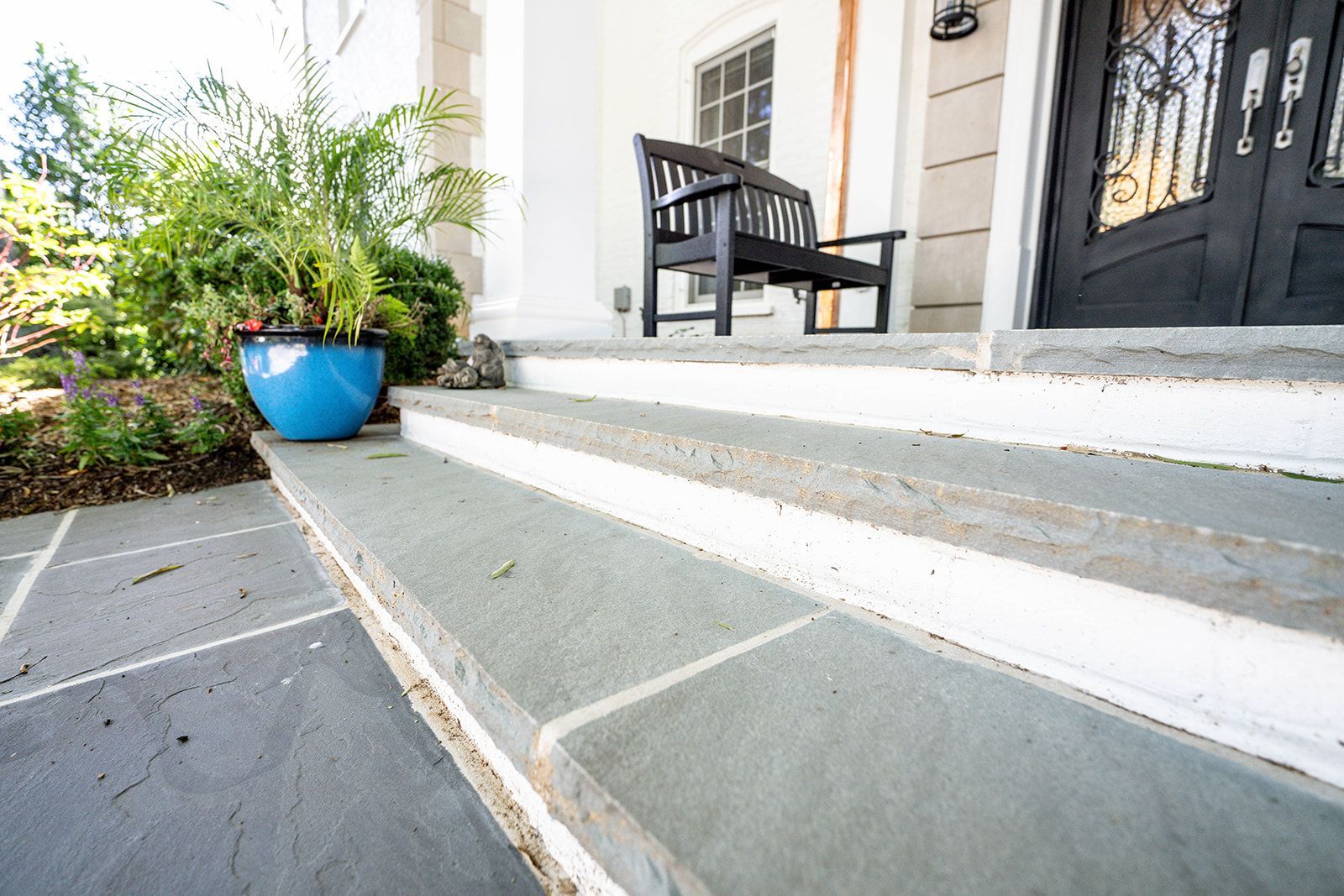 A black bench is sitting on the porch of a house.