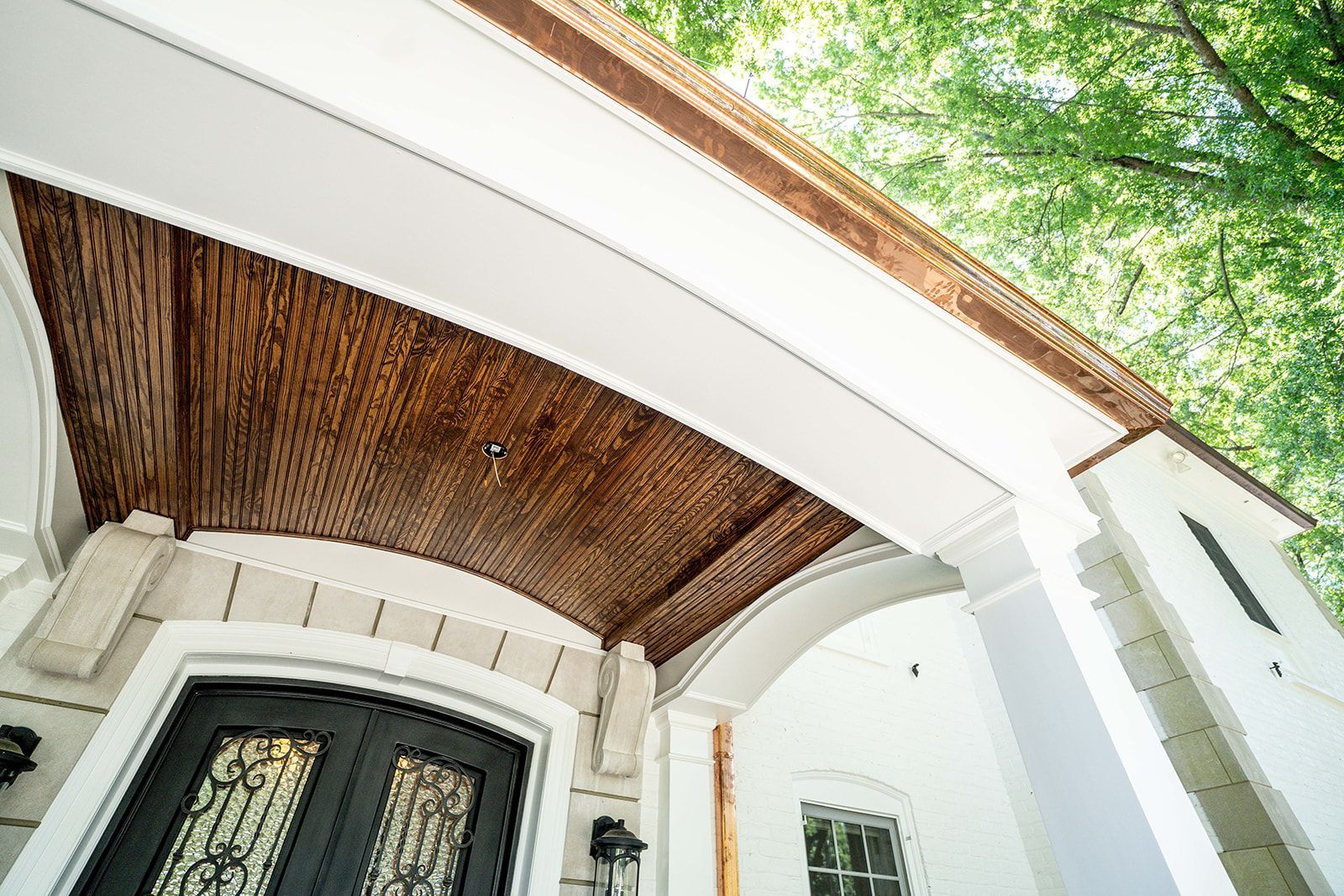 A white house with a black door and a wooden ceiling.