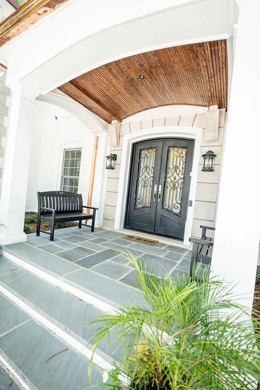 There is a bench on the porch of a house.