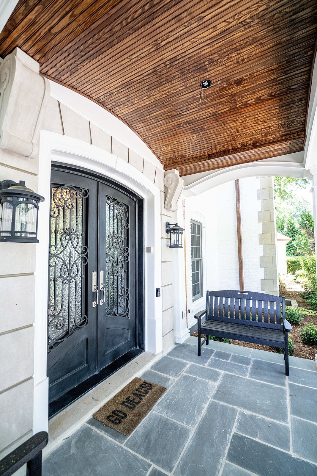 A porch with a bench and a welcome mat on it.
