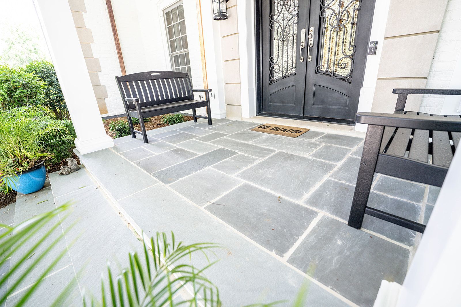 A porch with a bench and chairs in front of a house.