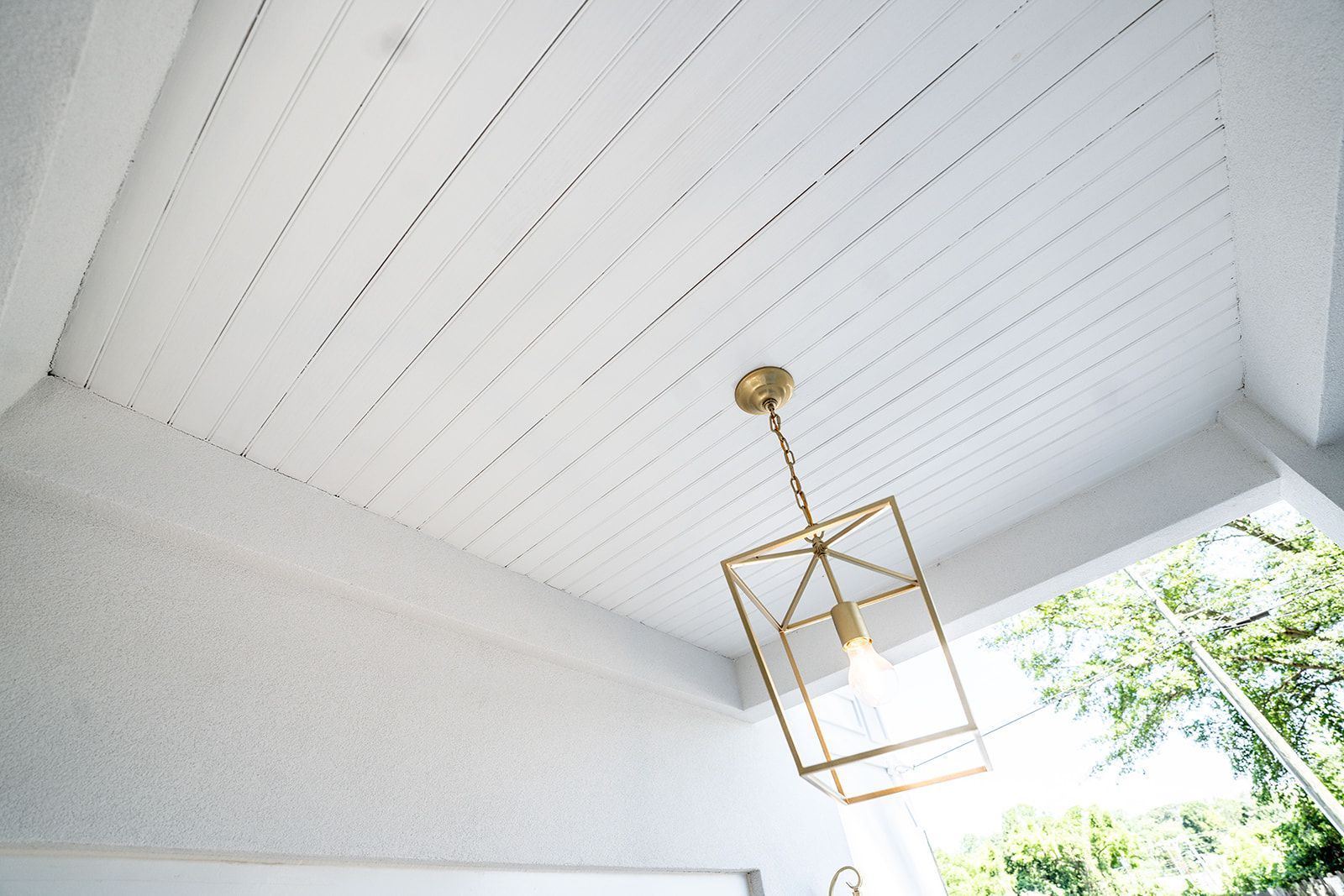 A pendant light is hanging from the ceiling of a porch.