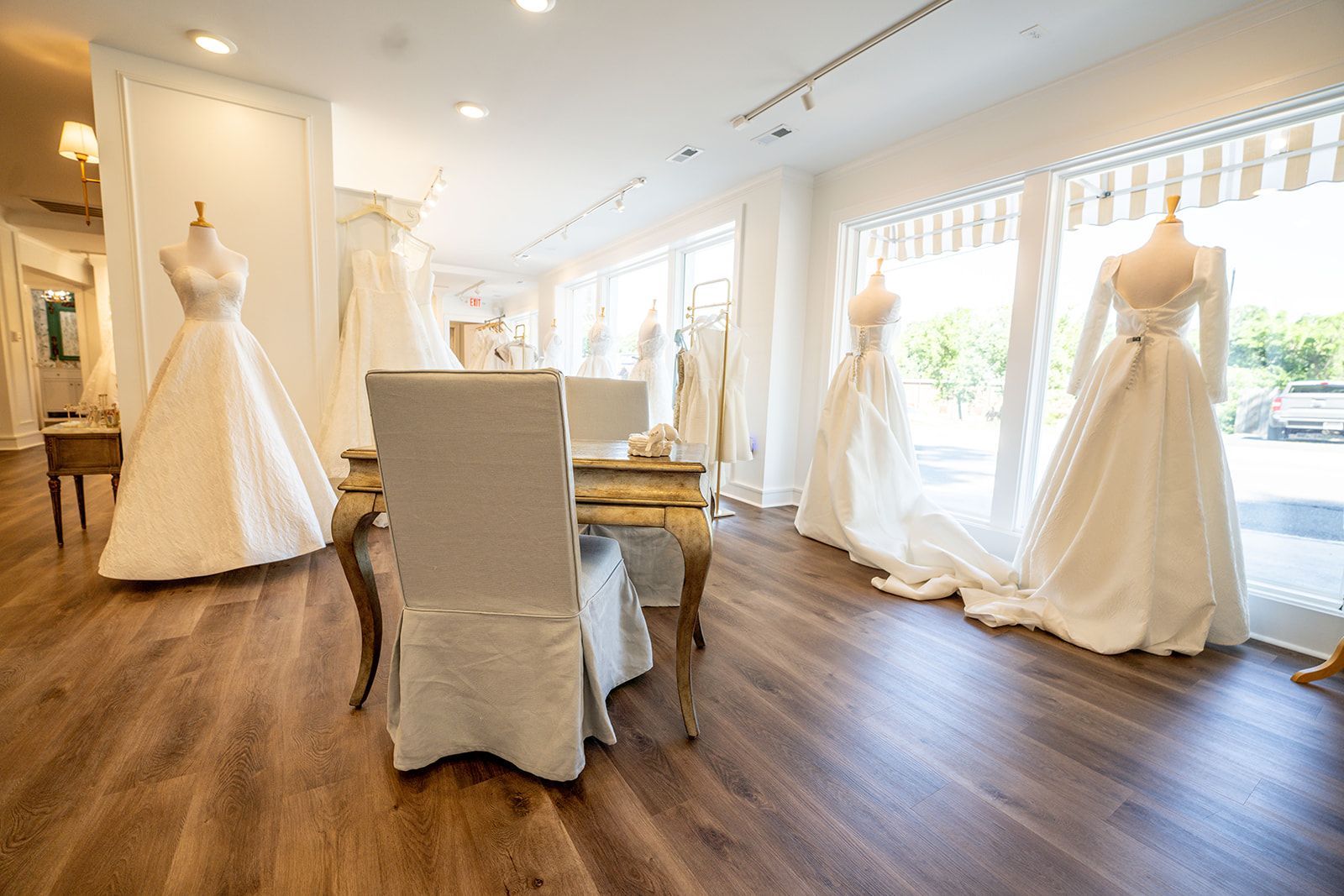 A room filled with lots of wedding dresses on mannequins.