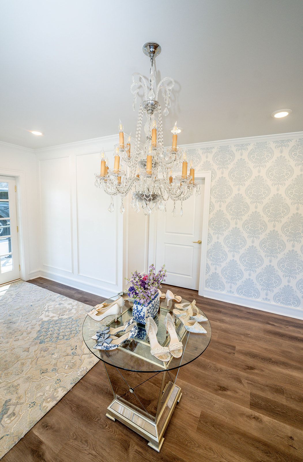A dining room with a round table and a chandelier hanging from the ceiling.