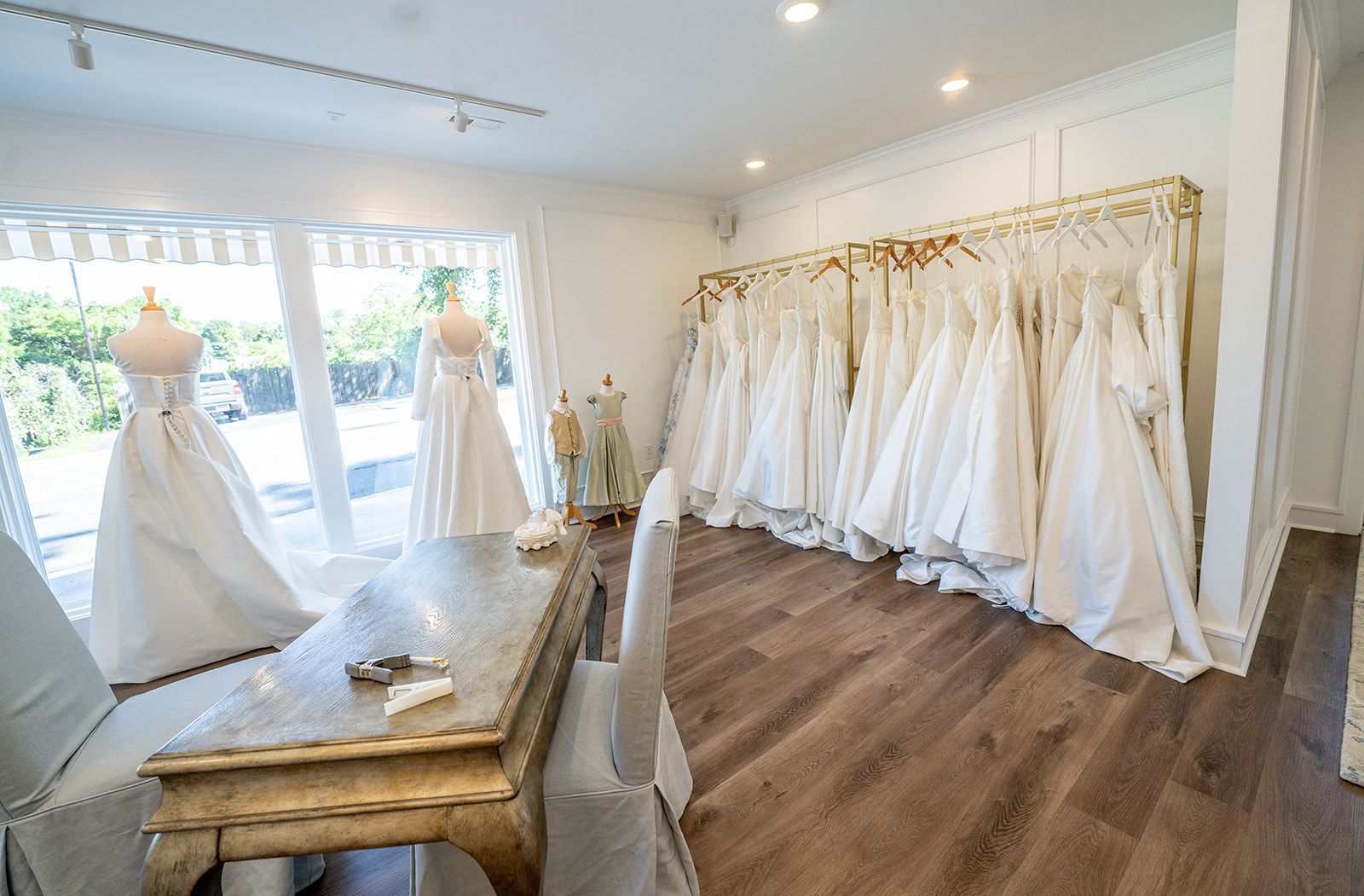 A room filled with lots of white dresses hanging on racks.