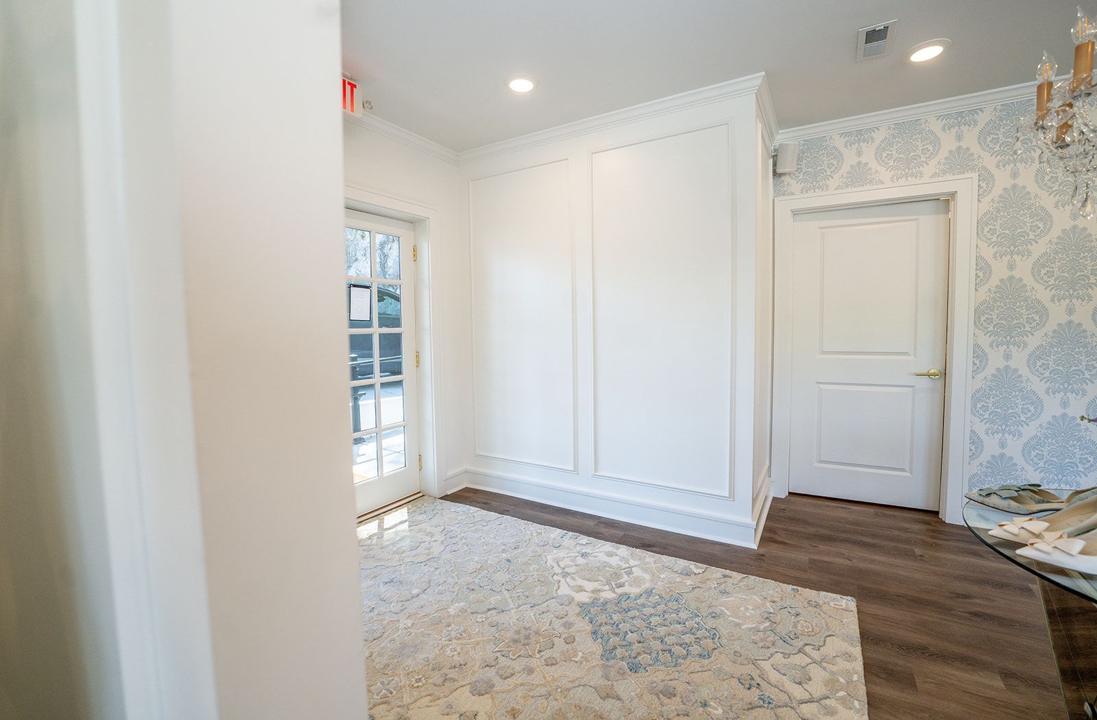 A room with a rug , white walls , and a door.