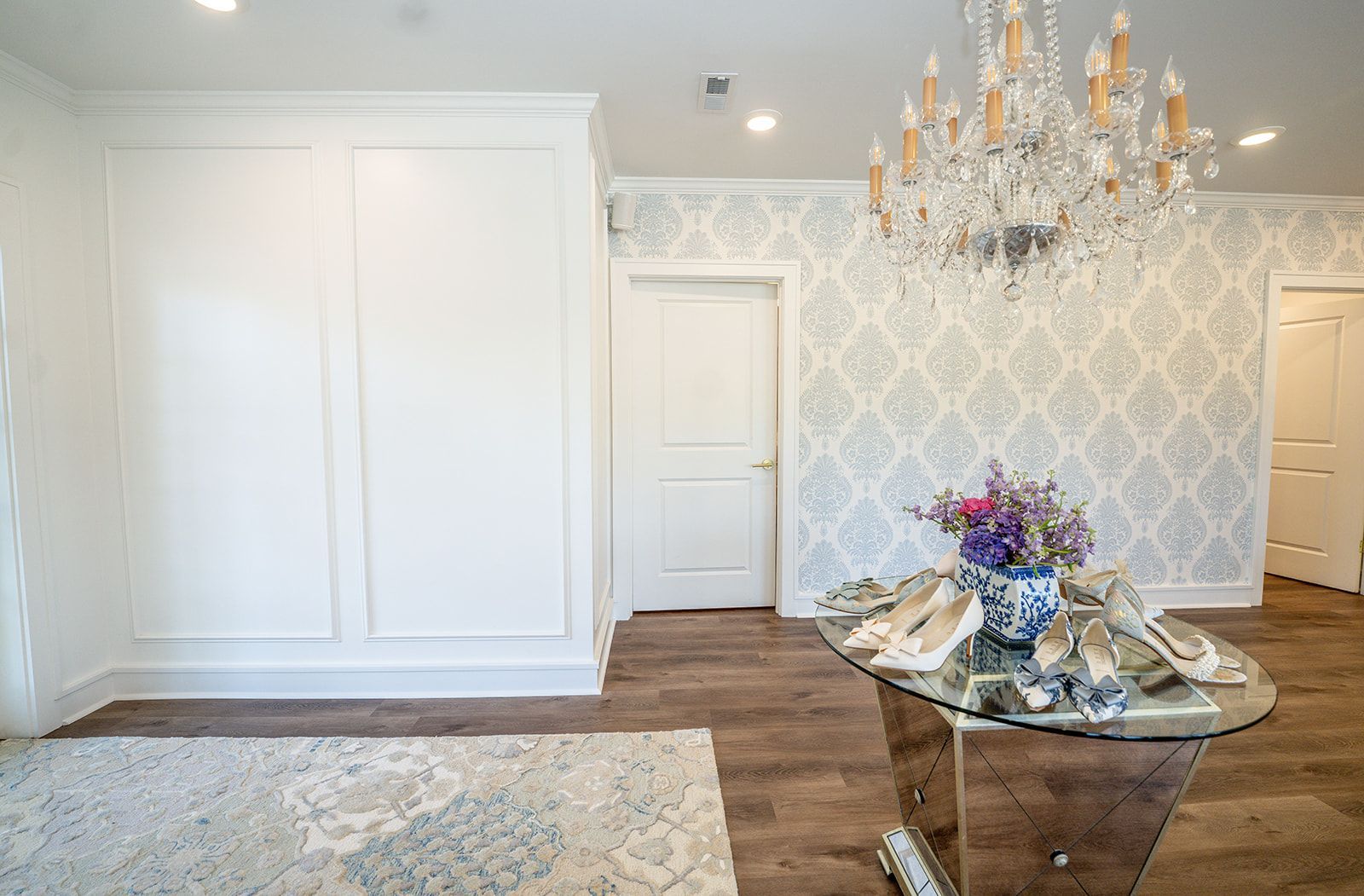 A dining room with a glass table and a chandelier.