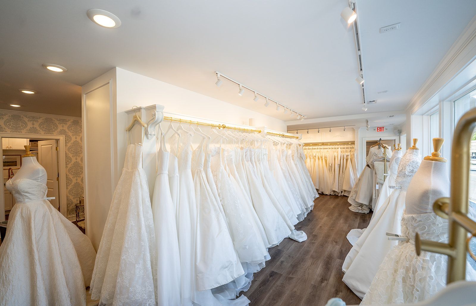 A room filled with lots of white wedding dresses on mannequins.