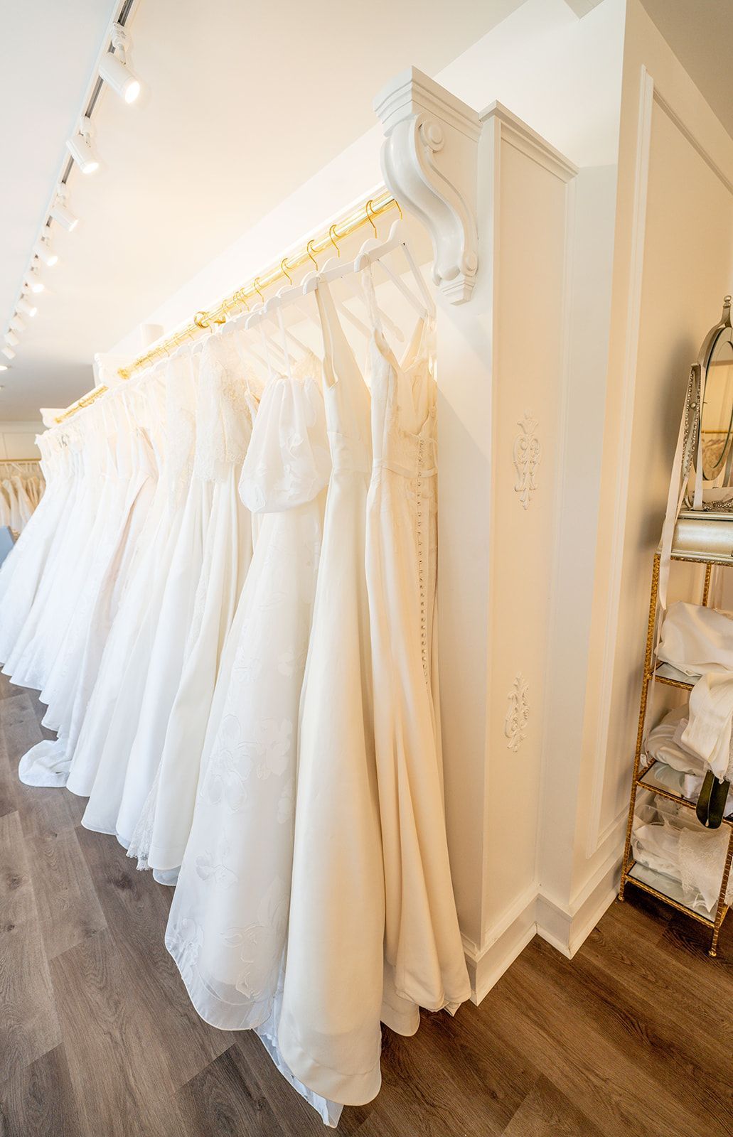 A row of white wedding dresses hanging on a rack in a bridal shop.