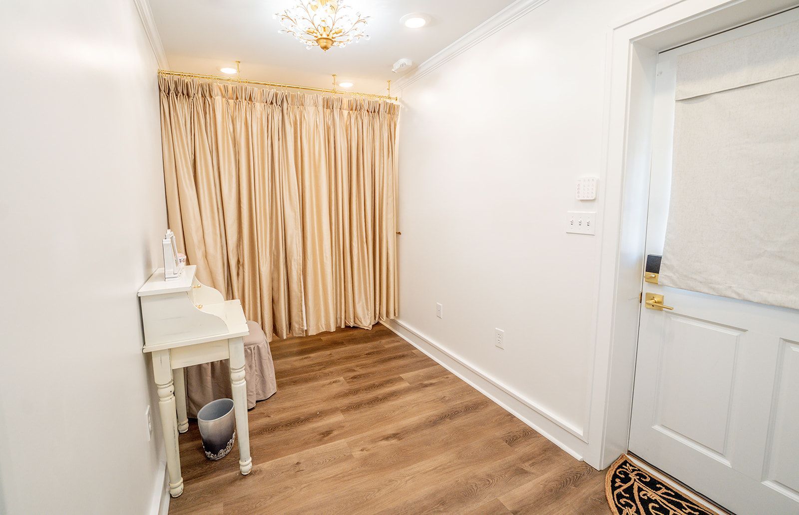 A room with hardwood floors , white walls and curtains.