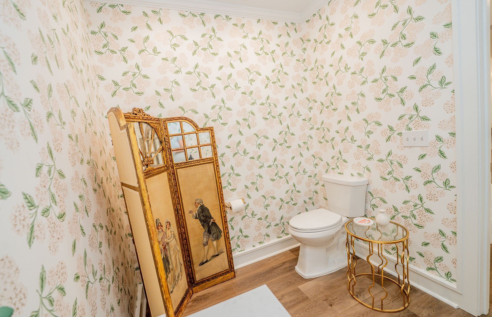 A bathroom with a toilet , a screen , and a table.