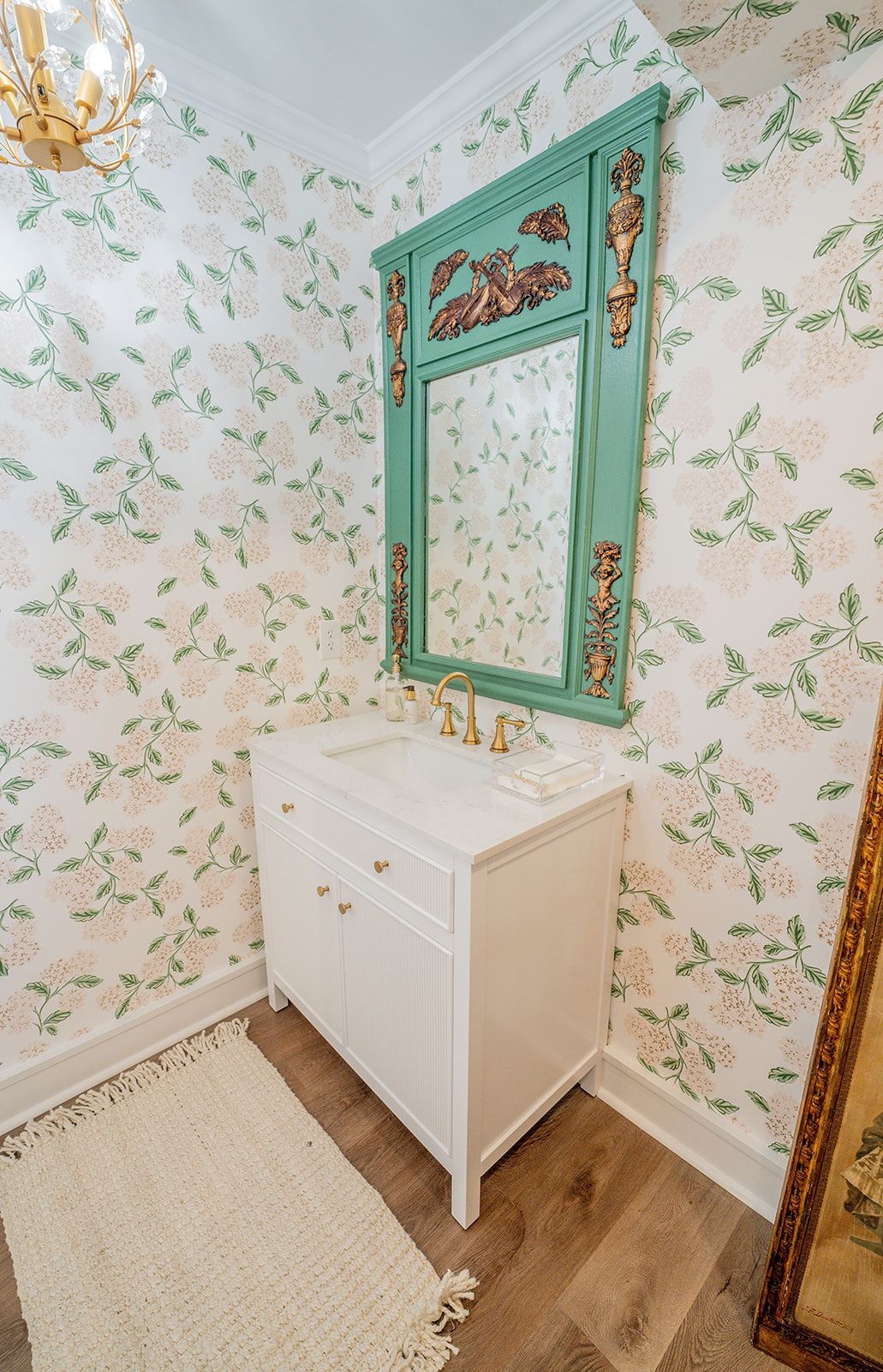 A bathroom with a sink , mirror and floral wallpaper.